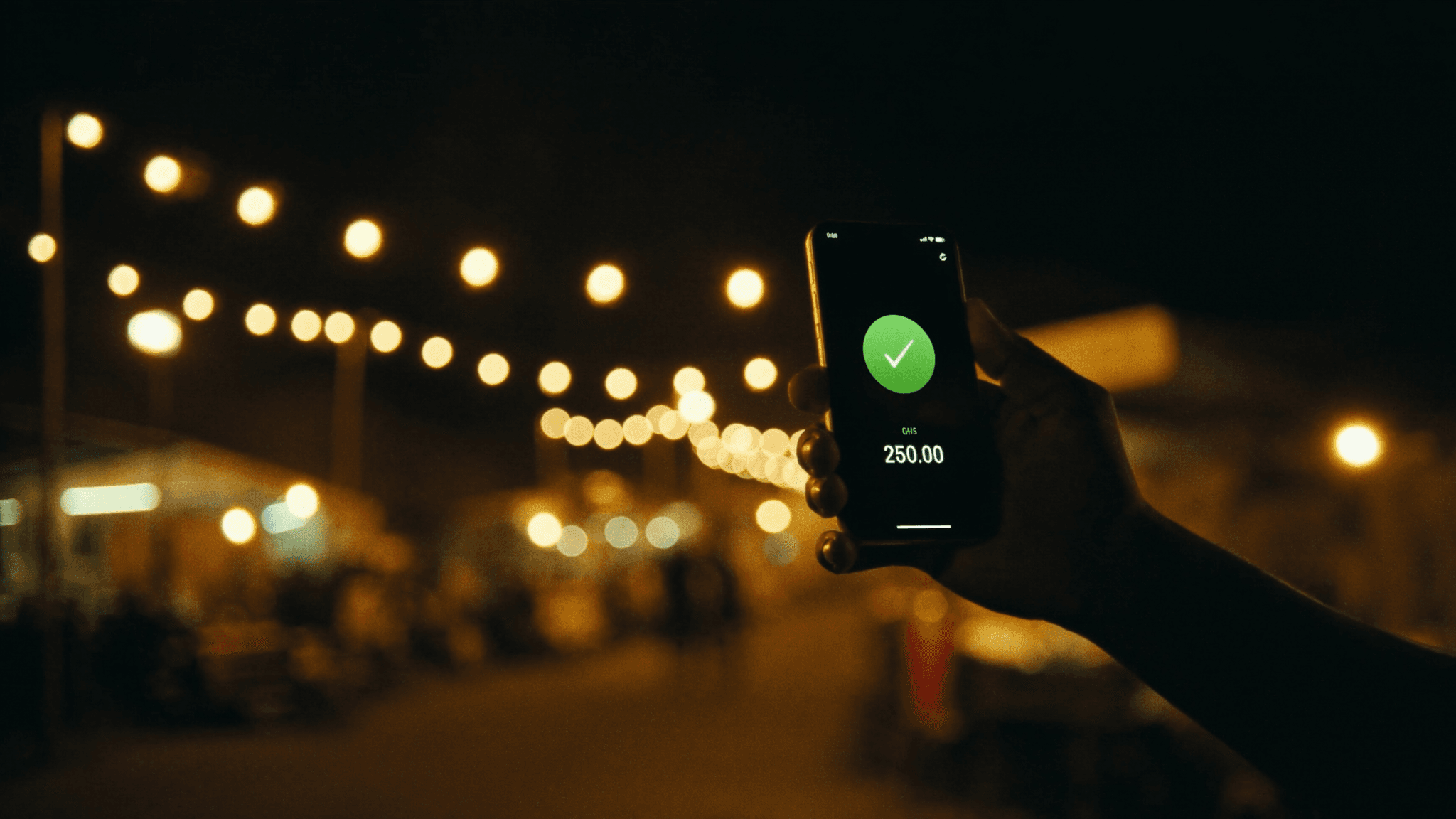A hand holding a phone at night, showing a successful GHS 250 payment.