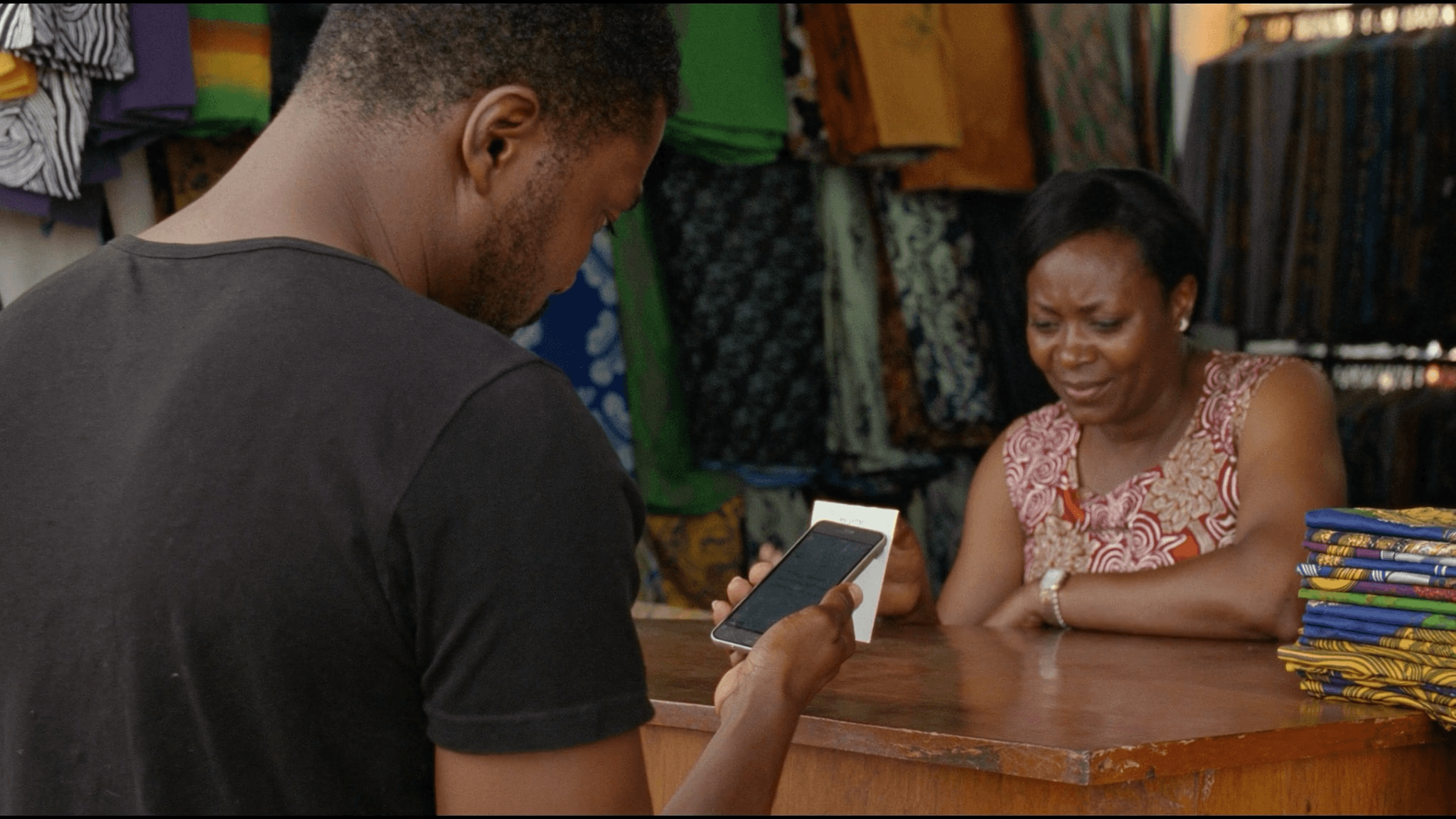 A customer paying a fabric merchant at the stall from a phone.